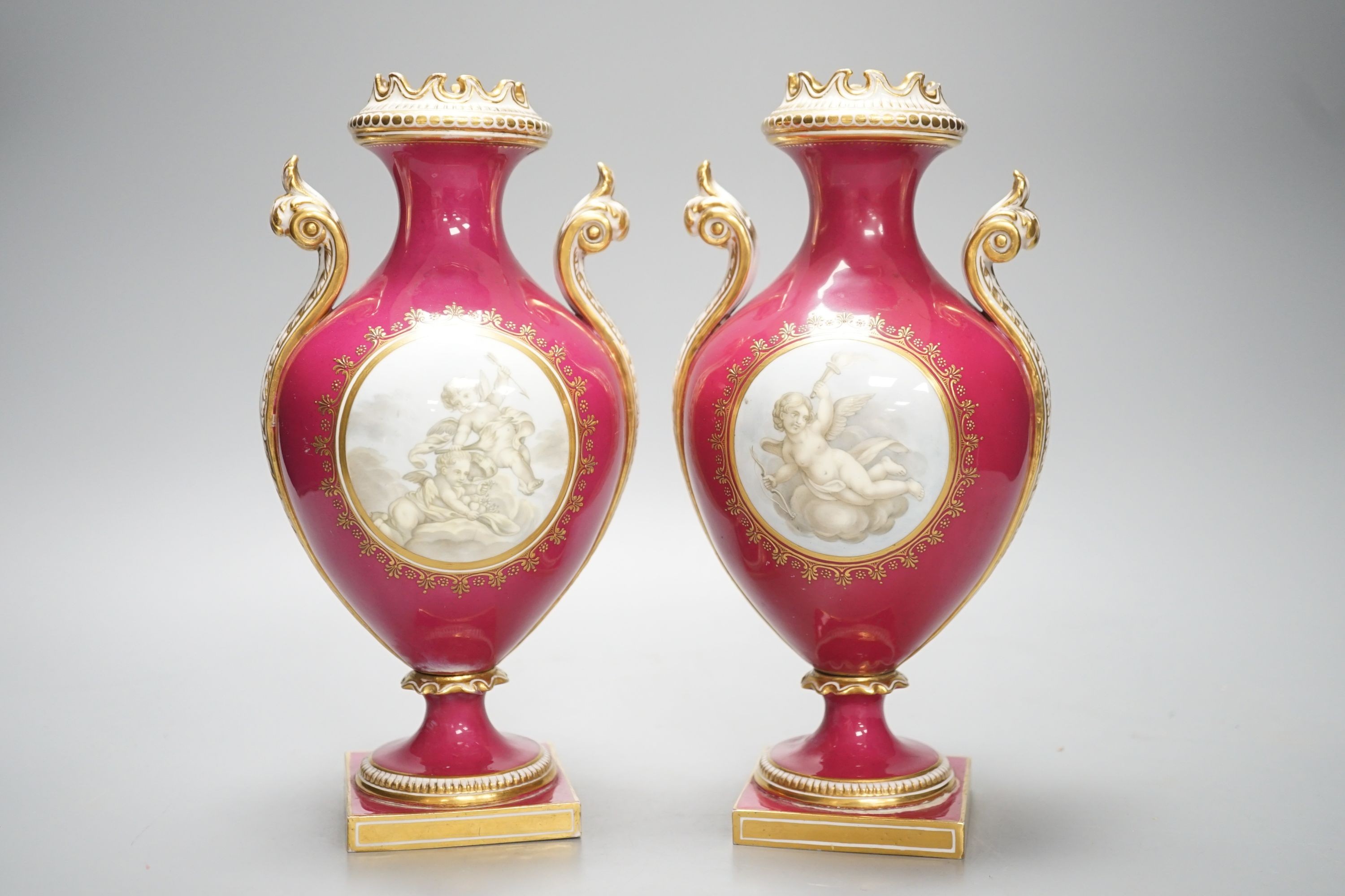 A pair of Coalport vases painted en-grisaille with cherubs in Chelsea style on a crimson ground, CSN mark in gold to one, height 23.5cm